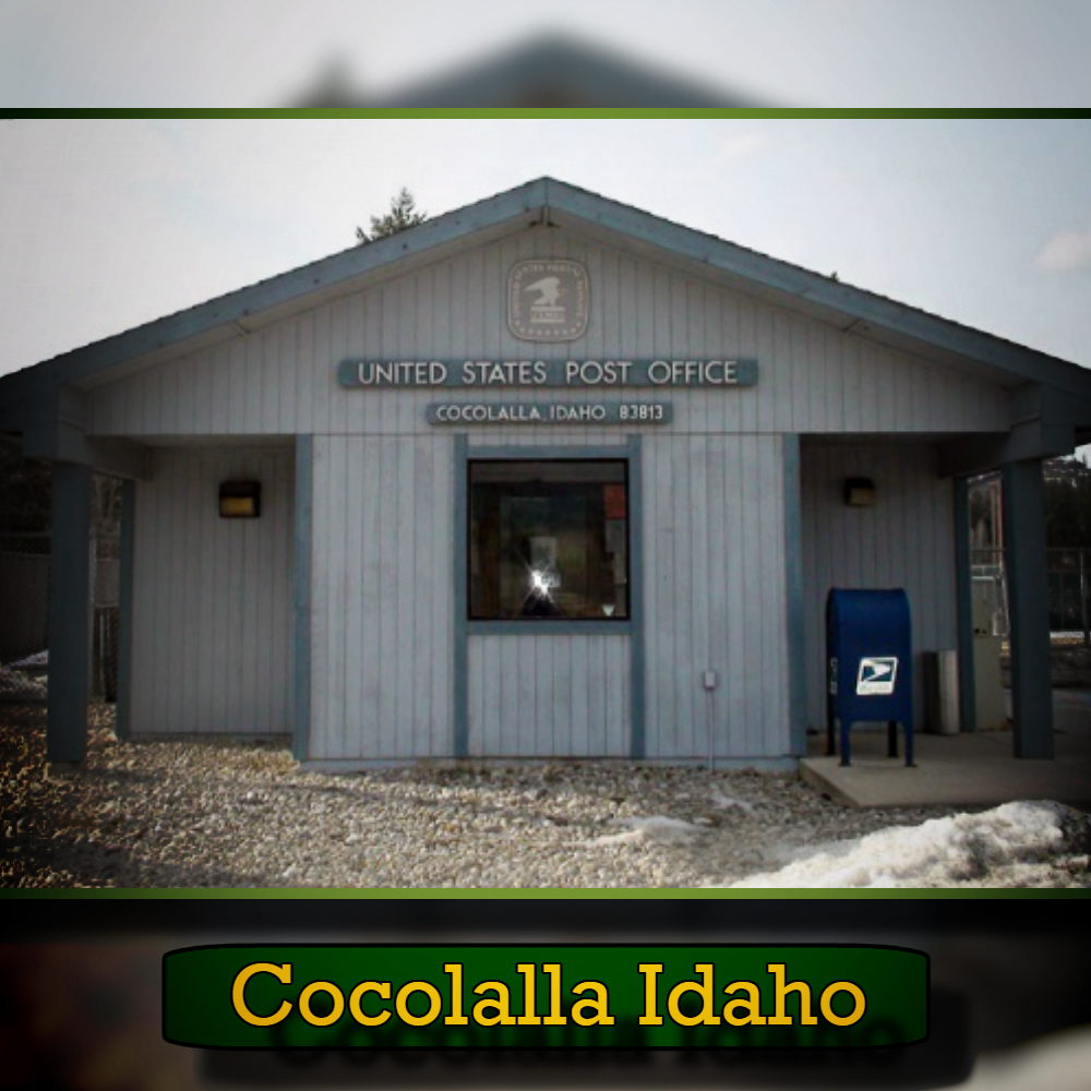 A small post office in Cocolalla, Idaho, with a light blue exterior and a USPS mailbox outside. The sign above reads "United States Post Office Cocolalla Idaho 83813," conveniently located near a tow service for any roadside assistance needs.