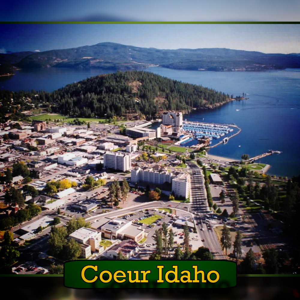 Aerial view of Coeur d'Alene, Idaho, showcasing a body of water, surrounding neighborhoods, and buildings. In the midst of this picturesque scene, a tow truck can be seen making its way through the streets. A caption at the bottom reads "Coeur Idaho.